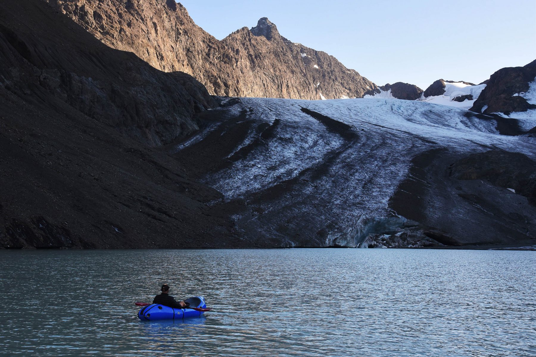 Greg Marin paddling an Alpacka Gnarwhal packraft on the unnamed lake below Flute Glacier